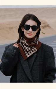 Detailed knit texture of brown and black houndstooth scarf worn in desert setting