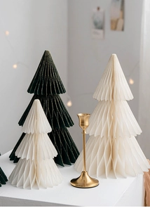 Close-up of honeycomb paper Christmas trees in dark green and cream with golden candle holder