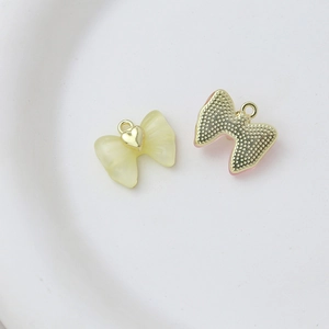 Detailed view of heart bow jewelry pendants with translucent yellow resin and gold metal base