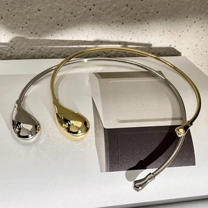 Macro detail of minimalist gold and silver teardrop chokers with a polished mirror finish