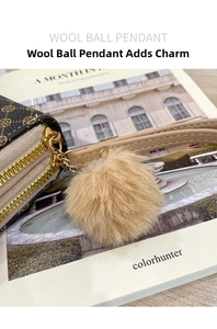 Detail of faux fur pom-pom charm and golden double zipper on floral long wallet
