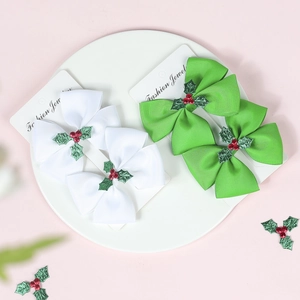 Close-up of Christmas bow hair clips with holly leaves and red berries on a ceramic plate