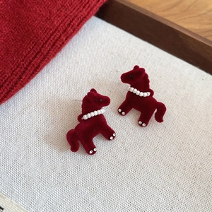 Gros plan de boucles d'oreilles cheval rouges avec collier de perles et strass brillants