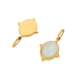 Macro shot of oval gold-plated pendant with white stone inlay and beaded edge details