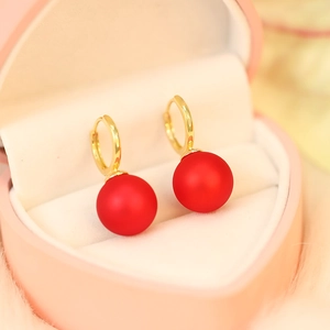 Detail of red matte bead earrings with gold hoops displayed in a heart-shaped jewelry box