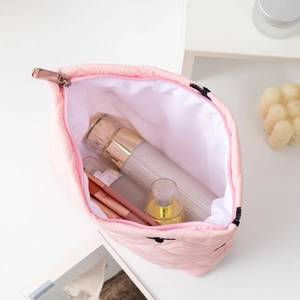 Top view of pink quilted cosmetic bag showing spacious interior with brushes and skincare