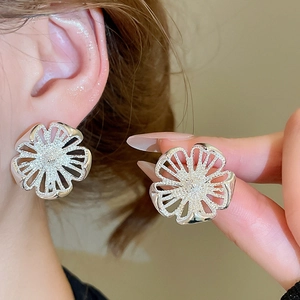 Nahaufnahme der silbernen hohlen Blumenohrstecker, getragen von einem Modell