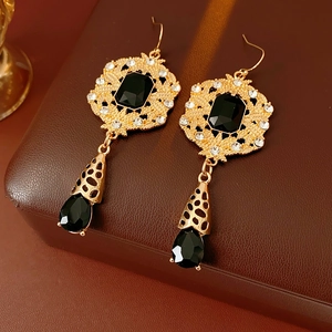 Detailed view of vintage gold drop earrings with black stones on leather texture