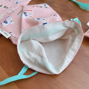 Close-up of pink cotton drawstring bag with white duck print and mint green rope