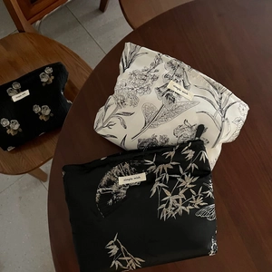 Three jacquard makeup bags with vintage floral and bamboo patterns on a wooden table