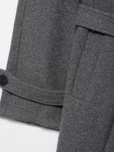 Detail view of dark grey wool coat featuring button cuffs and high-quality fabric texture