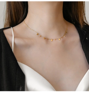 Detail view of a minimalist gold titanium steel necklace worn on a neck and collarbone