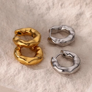 Detail of gold and silver hoop earrings featuring a unique textured lava effect design
