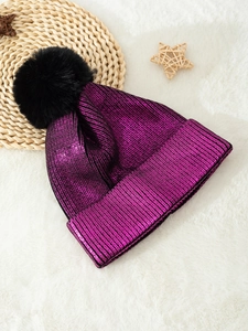 Detail of purple metallic knit beanie with large black faux fur pom pom and cuffed design