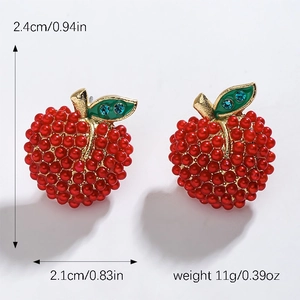 Details von roten Apfel-Ohrsteckern mit Perlenstruktur und blauen Kristallblättern