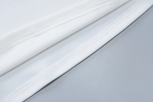Gros plan sur la texture du tissu en dentelle blanche montrant les coutures et la matière