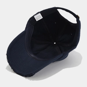 Detail view of navy blue distressed cotton baseball cap with embroidered bee and inner label