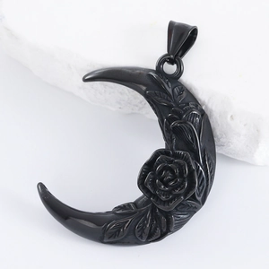 Macro detail of black crescent moon pendant with rose and leaf embossing on white stone