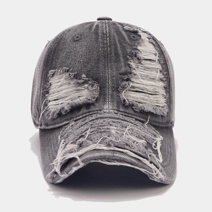Detail of distressed dark grey denim baseball cap with vintage frayed holes and raw edges