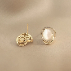 Elegant gold cat eye stone stud earrings with small zircon accents on beige silk