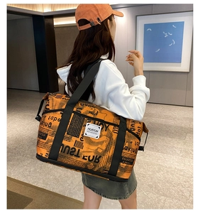 Detail of orange newspaper print travel bag showing expandable base in lifestyle setting