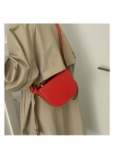 Close-up of a red semi-circular PU leather saddle bag with adjustable shoulder strap