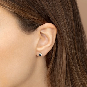 Elegant gold earrings with round dark blue sapphire zircon and white stone halo on ear