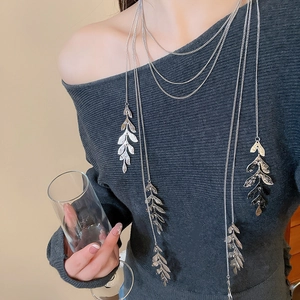 Detail of silver multi-layered leaf necklace worn on a charcoal grey sweater