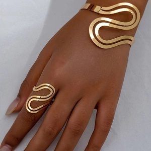 Macro detail of minimalist gold wavy bangle and adjustable ring set on a deep skin tone
