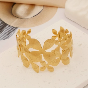 Detail of gold floral cutout cuff bracelet with hammered texture and brushed metal finish