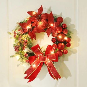 Christmas wreath with red poinsettia, baubles and LED lights hanging on a front door