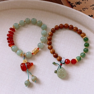 Detail view of jade and agate beaded bracelets with gourd and lotus pod charms