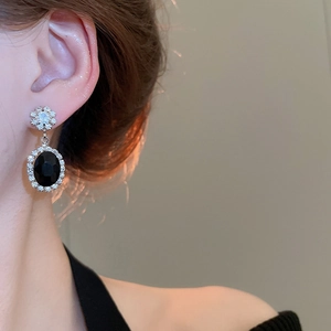 Detailed close-up of retro silver earrings with black zircon oval pendant and floral diamond studs