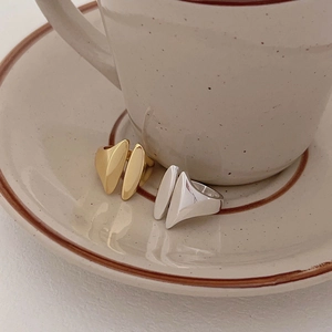 Detailed view of minimalist gold and silver open rings on a ceramic saucer