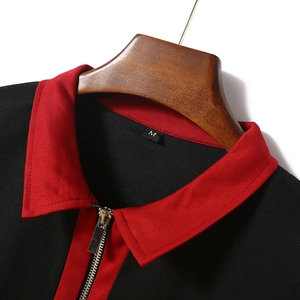 Detail of red and black color-block polo shirt featuring a metal zipper neckline and collar