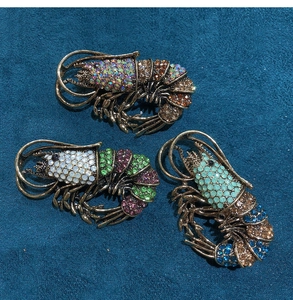 Close-up of vibrant rhinestone lobster brooches with colorful beads in various colorways