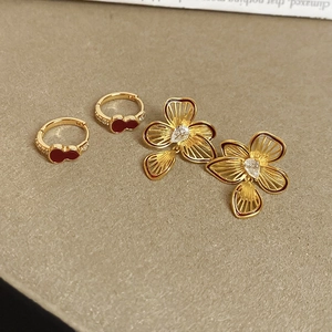 Detailed macro shot of gold flower earrings with a droplet-shaped zircon and red enamel gourds