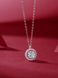 Macro view of 1-carat halo moissanite pendant on silver chain over a dark red backdrop