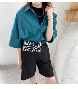 Chic teal shirt paired with black shorts and zebra print belt bag with gold chain details