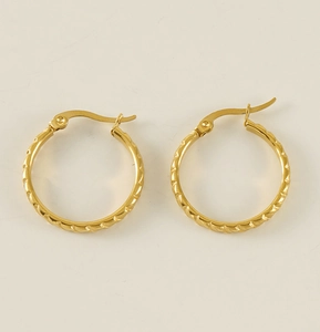 Close-up of golden twist texture hoop earrings on a clean off-white background