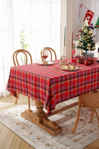 Festive red and green plaid tablecloth on a dining table with Christmas decor background