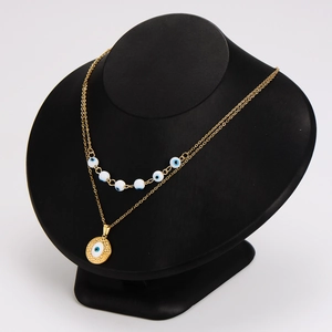 Gold double-layer necklace with blue eye beads and circular eye pendant on black mannequin