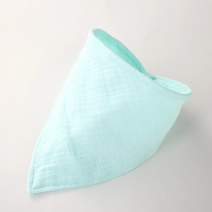 Détail d'un bavoir bébé vert menthe en mousseline montrant la texture douce du coton