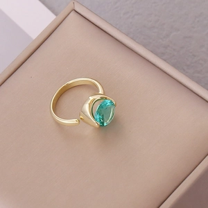 Detail of an open gold ring featuring a large oval-cut green gemstone on a velvet box