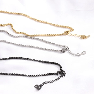 Detailed close-up of 26MM diamond cross pendants in gold, silver, and black on box chains