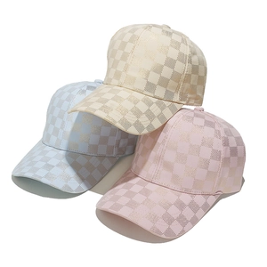 Three metallic checkerboard baseball hats in blue, beige, and pink with curved brims