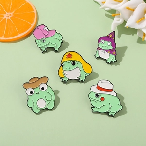 Detail of five green enamel frog pins wearing various colorful hats on a fresh background