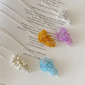 Detail view of grape cluster necklaces in five colors on artistic book background