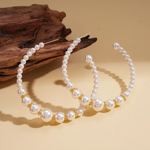 Elegant C-shaped pearl hoop earrings with gold beads on a natural wooden textured surface