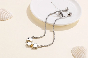 Detail of adjustable box chain bracelet with silver floral charms and gold bead accents